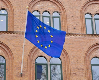 a european flag flying in front of a brick building